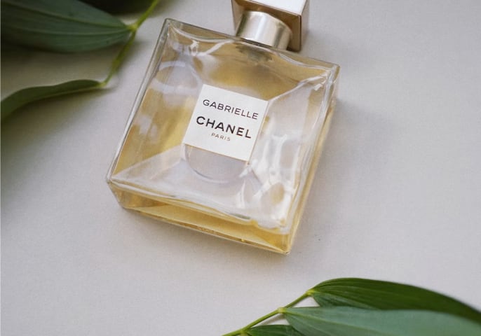 Chanel perfume bottle elegantly placed on a vibrant green leaf, showcasing nature's beauty and luxury in harmony.